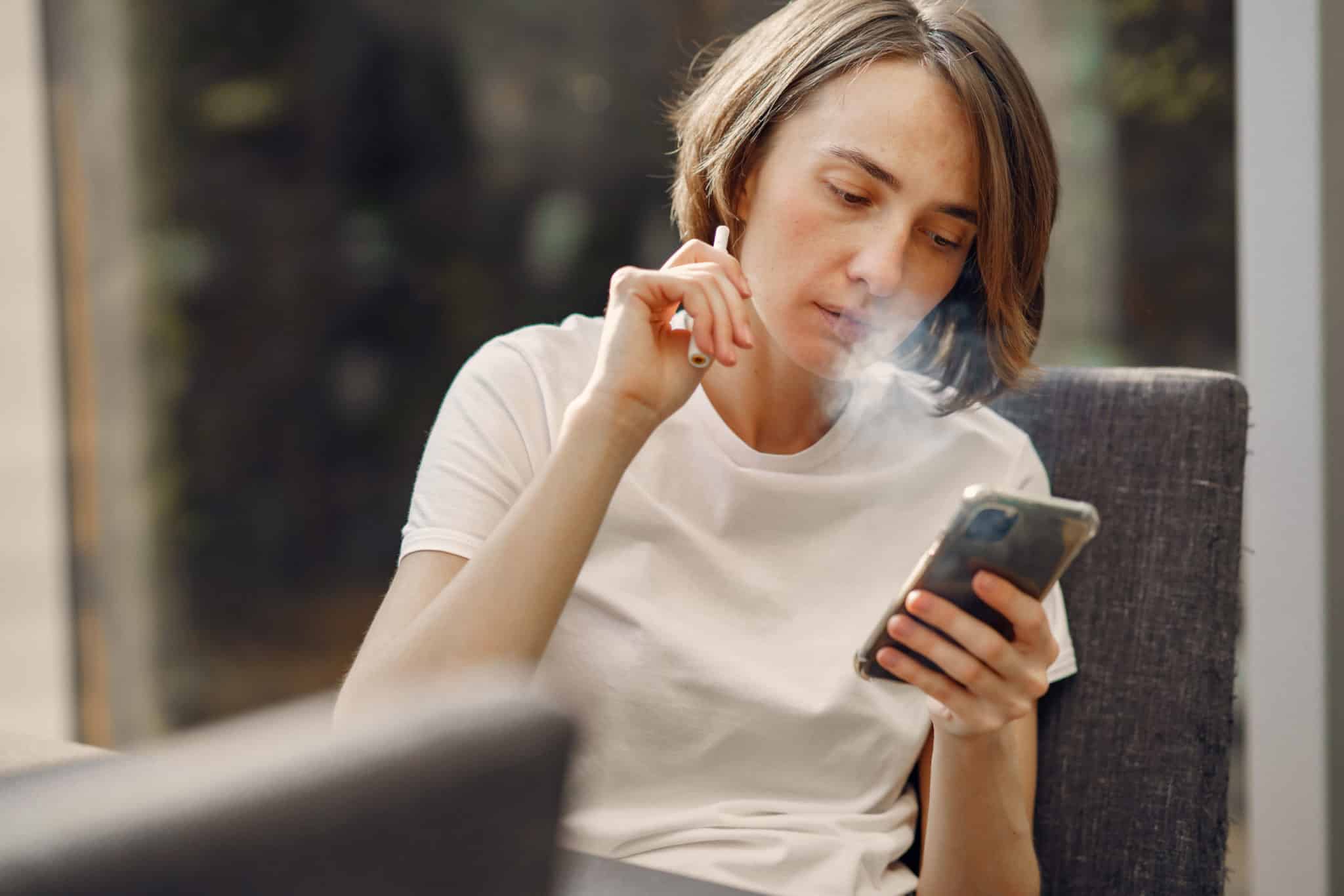 woman smoking while holding her phone