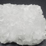 Pure THC-A diamond crystals shimmering with clarity on a dark surface.